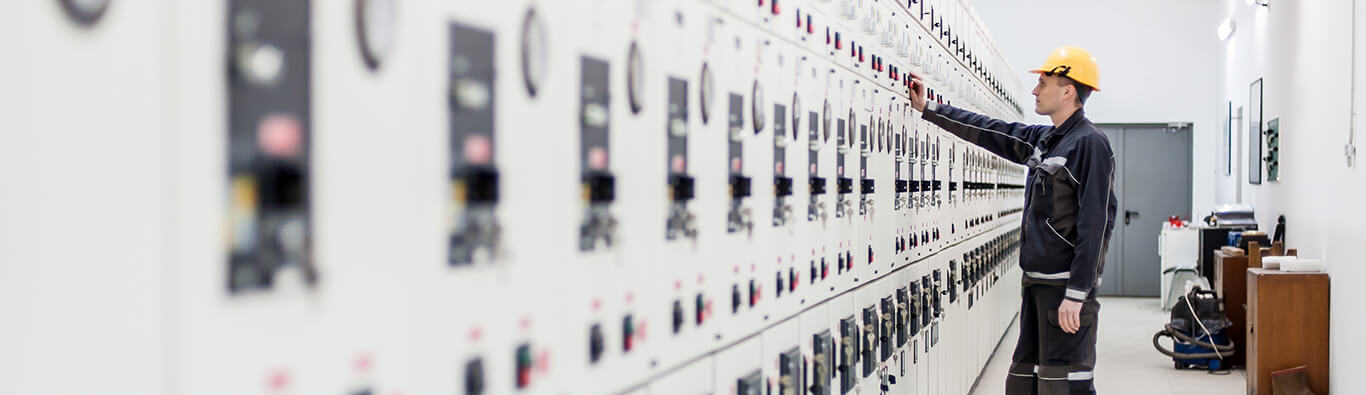 Engineer performing electrical testing on a switchgear panel using advanced diagnostic equipment in an industrial manufacturing facility