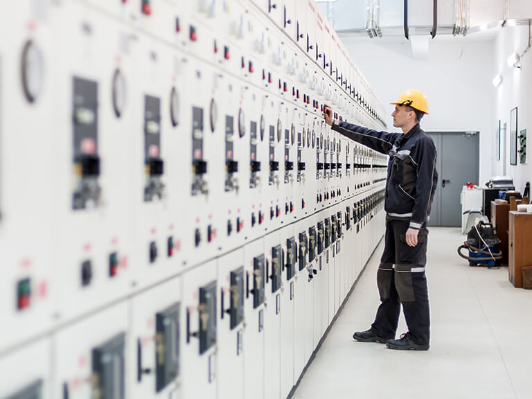 Engineer performing electrical testing on a switchgear panel using advanced diagnostic equipment in an industrial manufacturing facility